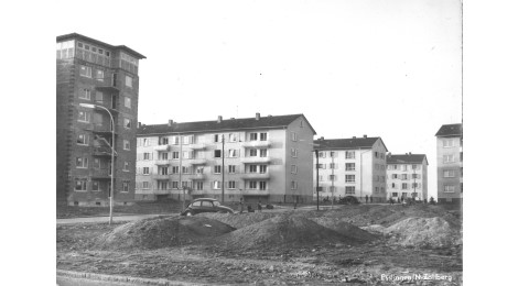 fertiggestellte Mehrfamilienhäuser im Hintergrund, davor Straßenbauarbeiten