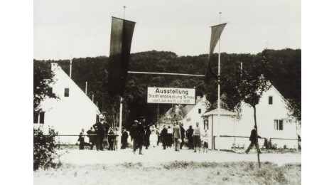 Eingangssituation der Ausstellung 1932 mit Fahnen und Hinweisschild